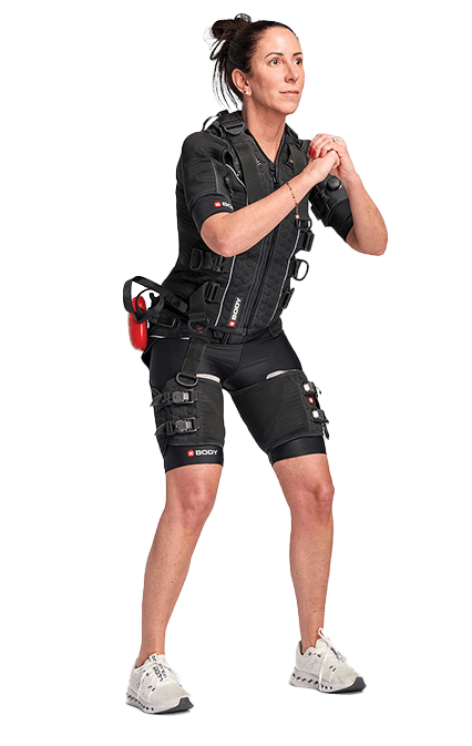 SOMA Fit Club A woman stands in a squat position wearing an EMS training suit and white sneakers, demonstrating the efficiency of an EMS workout against a plain white background. EMS Training