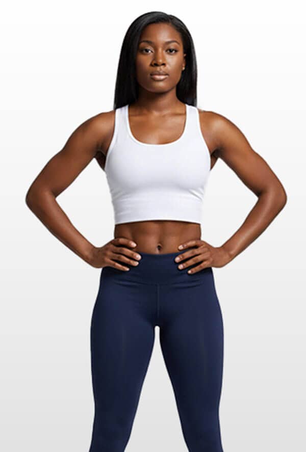 SOMA Fit Club A woman stands facing forward with hands on hips, wearing a white crop top and navy blue leggings against a plain, light background—ready for her EMS Training and efficient 20 Minute workout. EMS Training